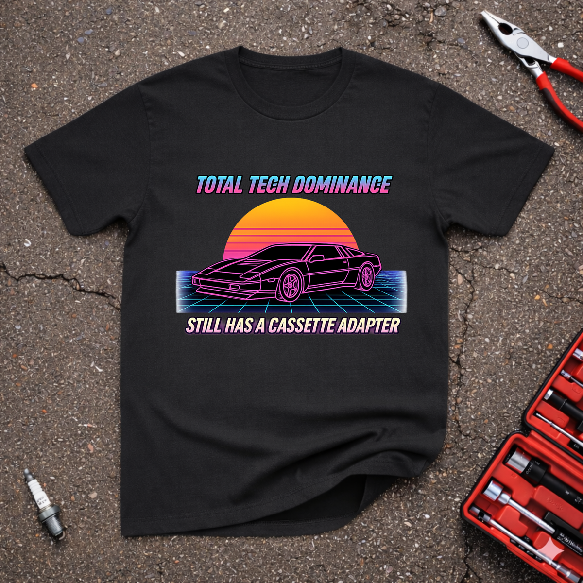 Tech Dominance funny retro automotive T-shirt with synthwave sports car, neon sunset, grid background, and text Still Has A Cassette Adapter on black shirt.
