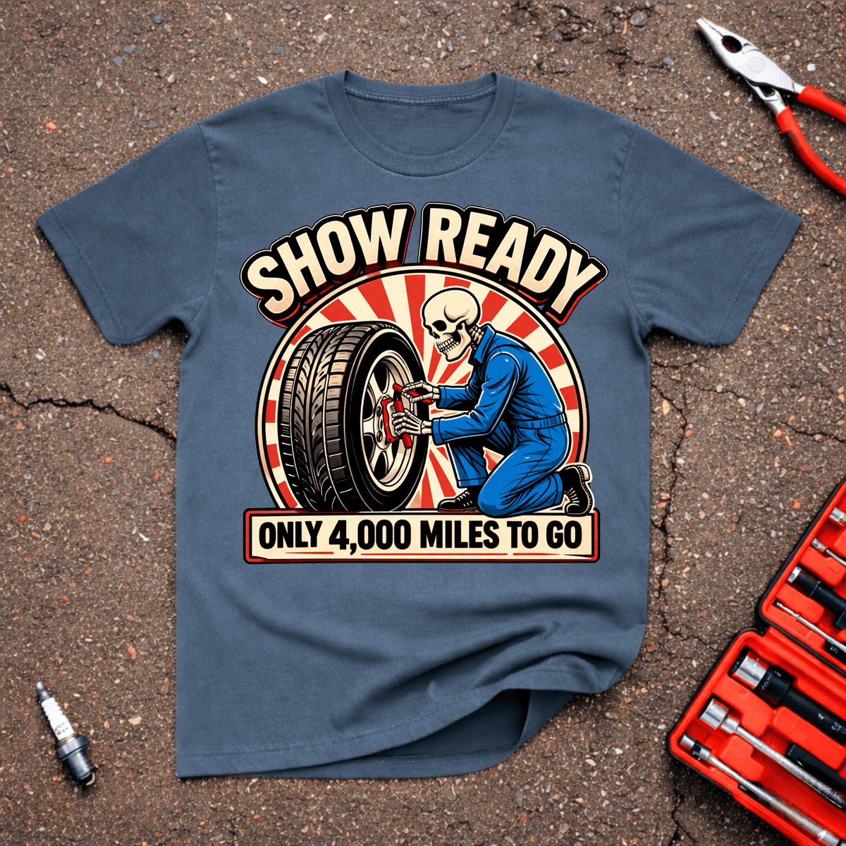 Show Ready funny car show T-shirt with skeleton mechanic servicing a wheel and text reading Show Ready Only 4,000 Miles To Go on Indigo Blue shirt.