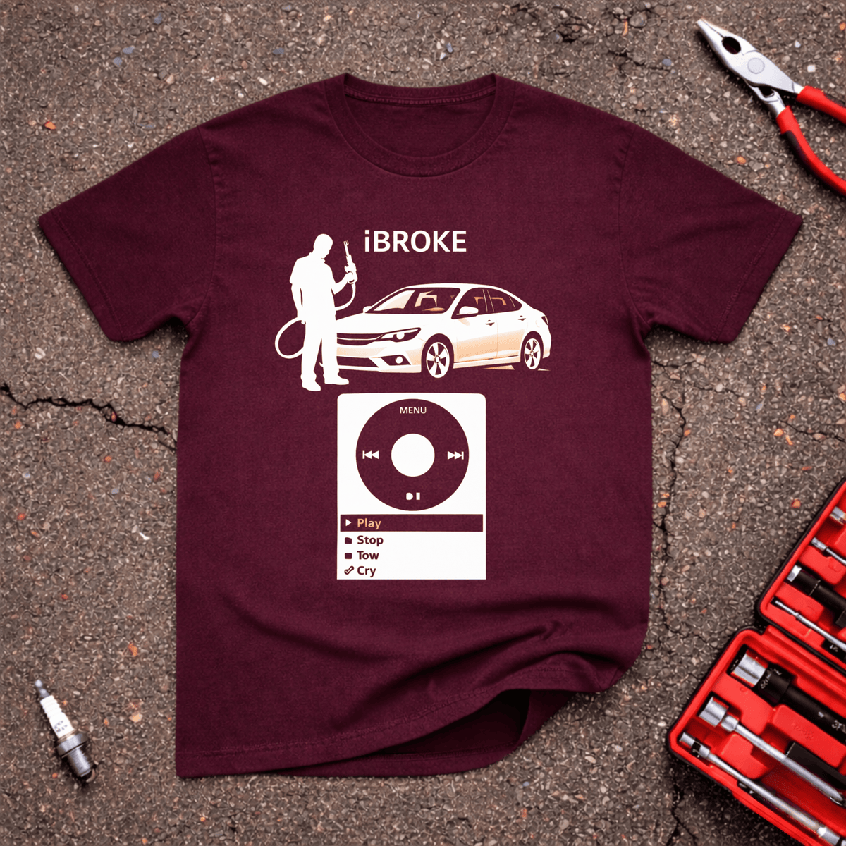 iBroke funny automotive T-shirt with broken-down white car, driver holding fuel nozzle, and retro music-player menu reading Play Stop Tow Cry on maroon shirt.