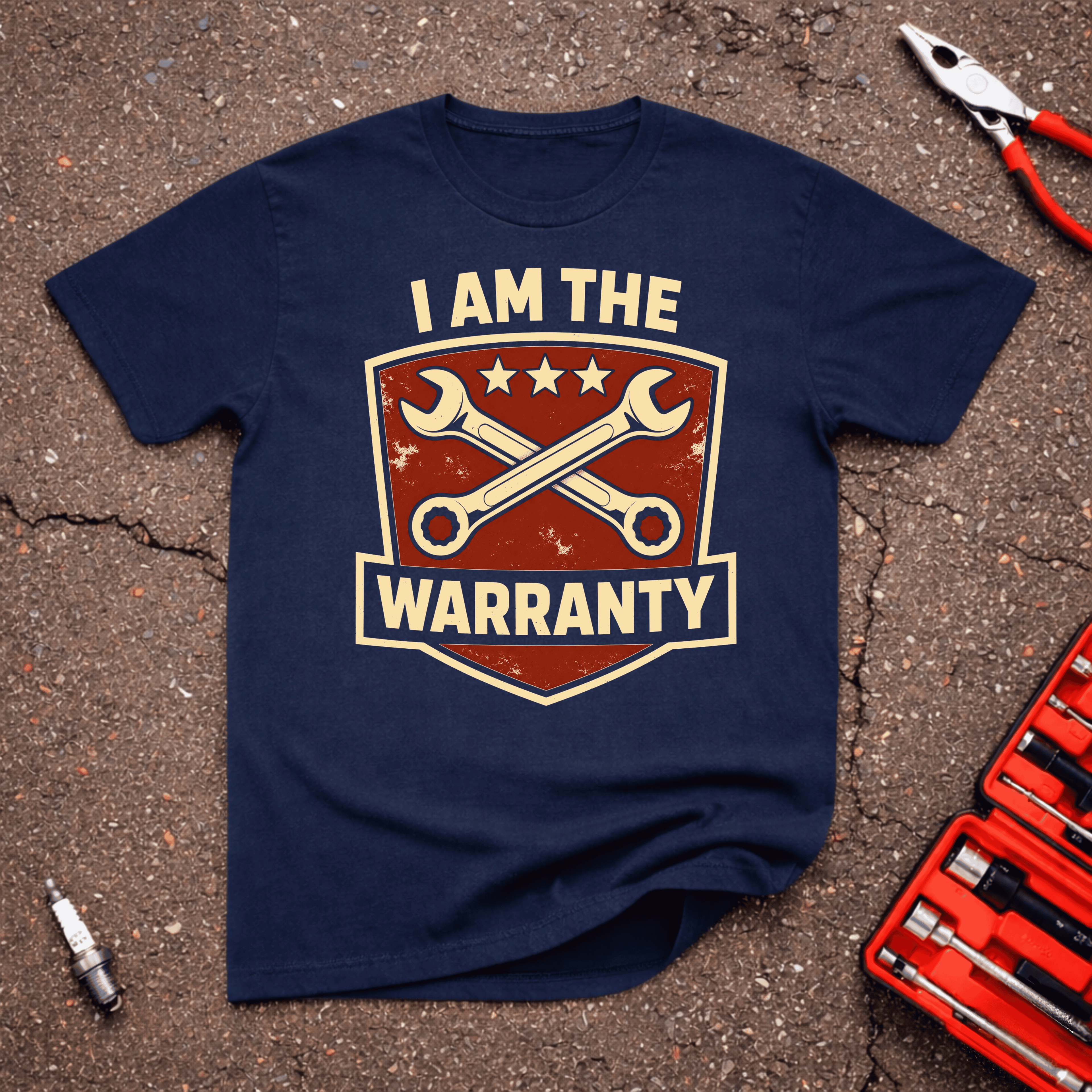 Warranty navy automotive humor t-shirt with a distressed red shield, crossed cream wrenches, three stars, and bold I Am the Warranty text — GarageGiggles.com apparel.