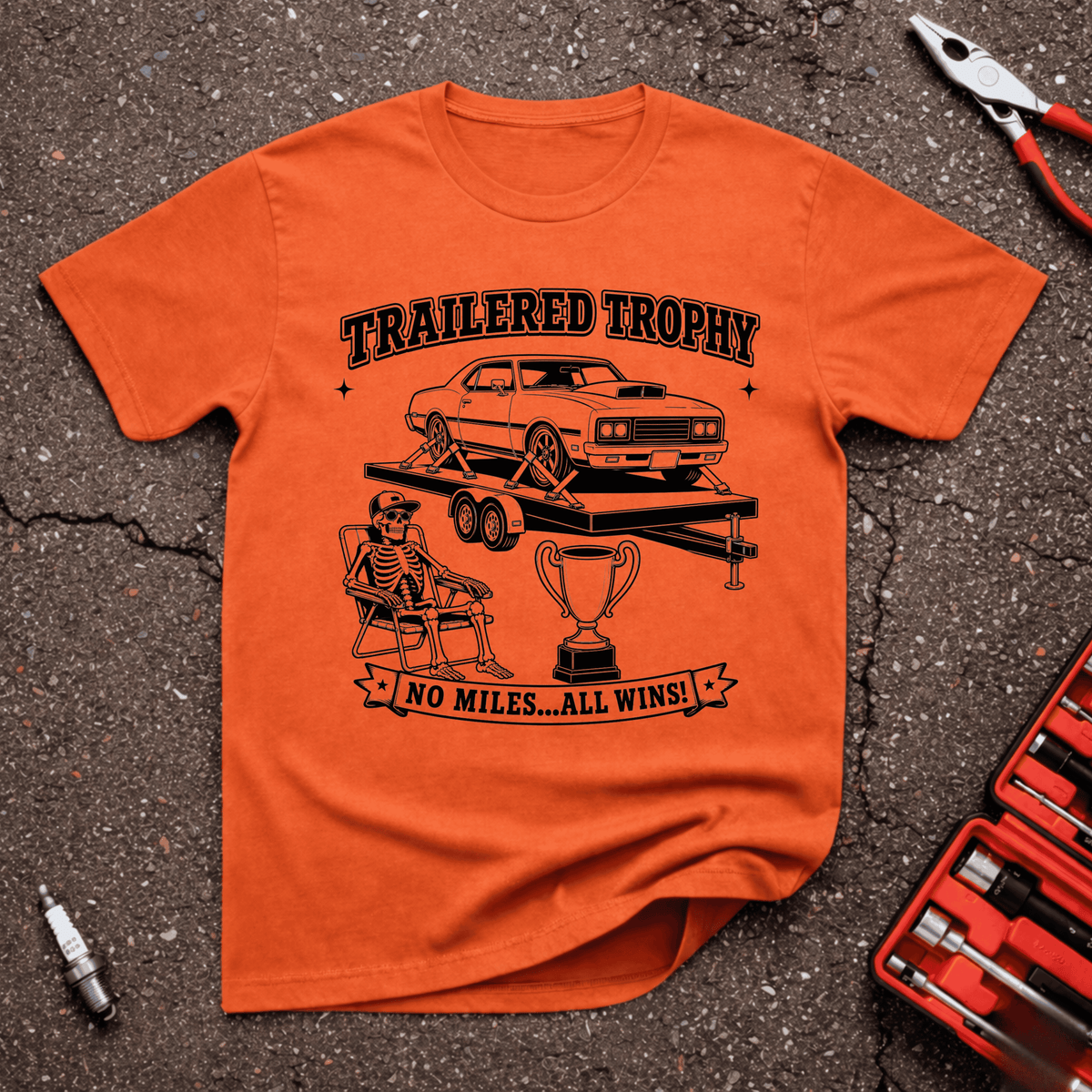 Trailered Trophy funny car show T-shirt with classic muscle car strapped to trailer, skeleton in lawn chair, trophy and No Miles All Wins text on orange shirt.