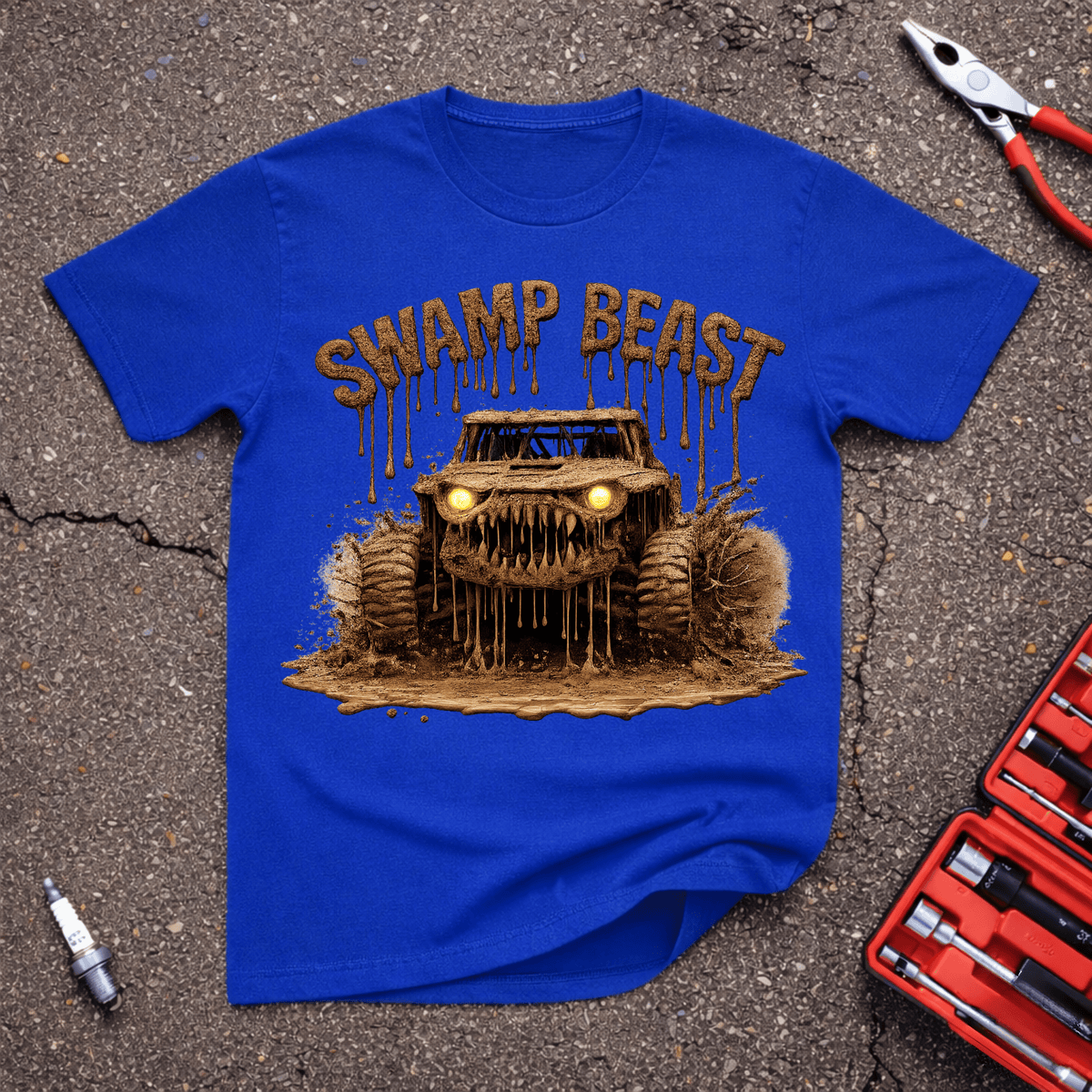 Swamp Beast funny off-road T-shirt with mud-covered monster truck, glowing yellow headlights, huge tires, fang-like grille, and dripping Swamp Beast text on Royal blue shirt.