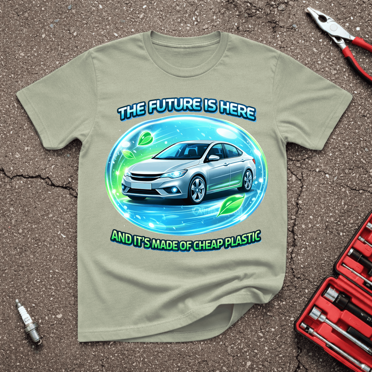 Future Is Here funny automotive T-shirt showing a futuristic silver car in a glowing blue and green bubble with text And It’s Made Of Cheap Plastic on Sage shirt.